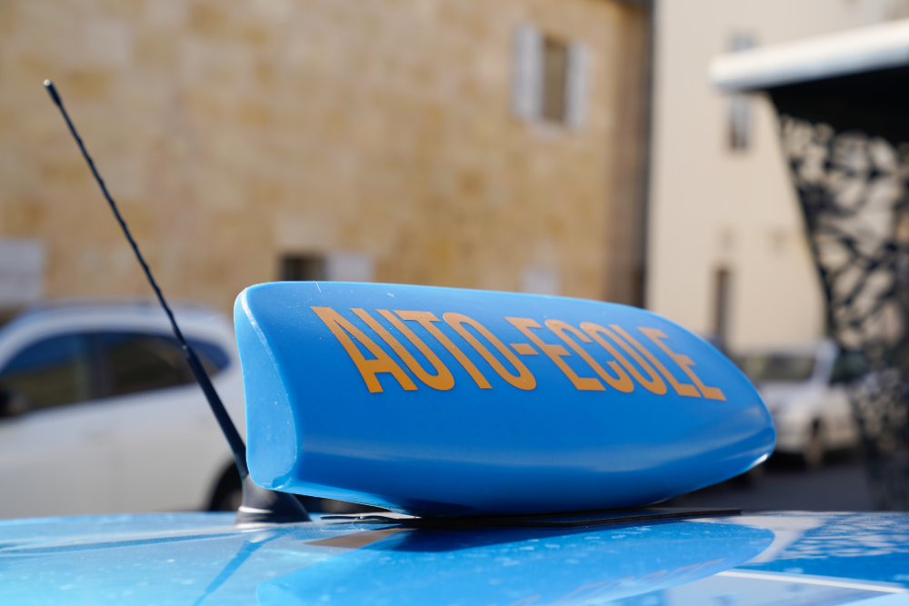 Signalétique "AUTO-ÉCOLE" bleue sur le toit d’un véhicule de formation stationné en ville, illustrant une auto-école à Lille.