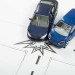 le bonus/malus en assurance automobile quand deux voitures miniatures entrent en collision sur un croisement dessiné au crayon, illustrant un accident de la route.