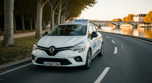 Voiture auto-école blanche circulant le long de la rivière Marne avec le pont de Château-Thierry en arrière-plan lors d'une leçon de conduite en fin de journée.